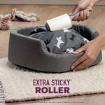 Lint roller being used on a gray pet bed next to a rug and dog toy with 'extra sticky roller' text