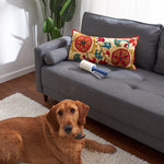 Lifestyle scene of a lint roller on a grey sofa with a dog lying on a rug nearby, suggesting pet hair cleaning use.