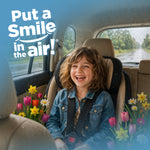 Smiling child in a car seat with floral graphics and slogan 'Put a Smile in the air!' promoting Little Duck air freshener