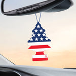 Patriotic Little Trees America air freshener hanging from a rearview mirror inside a vehicle against a soft sky backdrop.