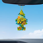 Be Kind tree air freshener suspended from a car rearview mirror against a clear blue sky and light clouds.