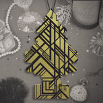 Gold-pattern Little Trees tree air freshener displayed on a stylized tabletop with watch and glassware props