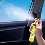 Hand spraying a Little Trees Vanillaroma bottle inside a vehicle, visible mist spraying toward window