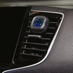 Little Trees vent clip attached to a vehicle air vent with visible blue liquid center and black plastic housing