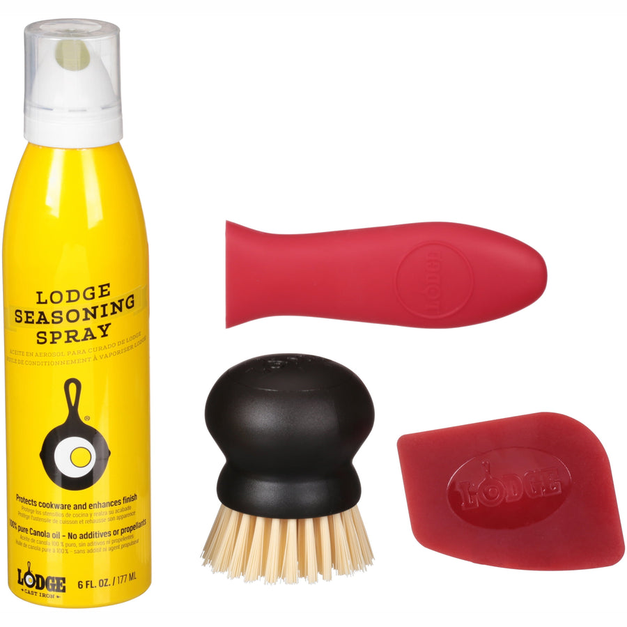 Flat lay of Lodge cast iron care kit items: yellow seasoning spray, black round brush and red silicone handle cover and scraper on white background.