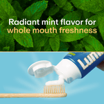 Close-up of fresh mint leaves above a toothbrush receiving white toothpaste from a Lumineux tube and radiant mint flavor text.