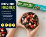 Bowl of fruit covered in clear wrap with Lunchskins compostable food wrap box and keeps food fresher graphic
