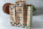 Three upright brown kraft Lunchskins lunch sacks with different prints on a kitchen surface