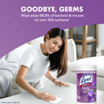 Woman cleaning a coffee table with a wipe in a living room scene and a Lysol Brand New Day lavender canister visible.