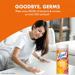 Person wiping a table with a Lysol Brand New Day mango & hibiscus wipes tub visible, headline about wiping away germs