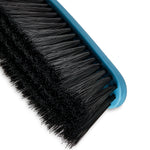 Close macro view of dense black broom bristles set into a blue plastic broom head