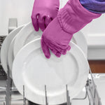 Pair of magenta rubber cleaning gloves being used to load or handle white dishes in a dishwasher rack.