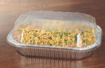 Rectangular aluminum baking pan filled with pasta and covered by a clear plastic hinged lid on a wood surface