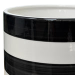 Close-up of the upper rim and top band of a glossy black and white striped ceramic planter