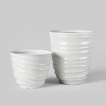 Studio shot of two cream ribbed plastic planters on a neutral grey background