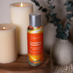 Mainstays Cranberry Mandarin room spray can styled on a wooden surface with candles and decorative vase in the background