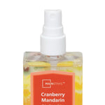 Close-up of the top half of a Mainstays Cranberry Mandarin spray bottle showing white spray nozzle and orange label