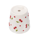 Underside of a cream ceramic cherry planter showing drainage hole and scattered cherry motifs