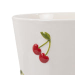 Close-up detail of raised red cherry design and green leaf on a cream ceramic planter