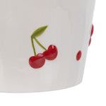 Cropped close-up of two red cherries painted on the lower side of a cream ceramic planter