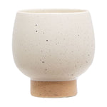 Cream speckled round ceramic planter with a short tan pedestal base on white