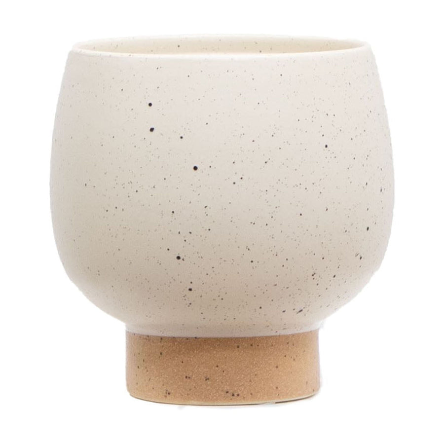 Cream speckled round ceramic planter with a short tan pedestal base on white