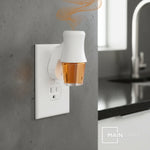 Amber fragrance oil refill in a plugged-in warmer on a kitchen wall outlet with subtle aroma vapor and Mainstays logo