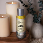 Mainstays Fresh Cotton room spray can styled on a wooden surface beside lit candles and a decorative vase.