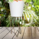 Mainstays gold metal plant stand holding a white planter on a wooden deck