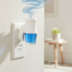 Mainstays fragrance oil refill inserted into a white wall plug-in warmer with blue liquid and decorative scent vapor