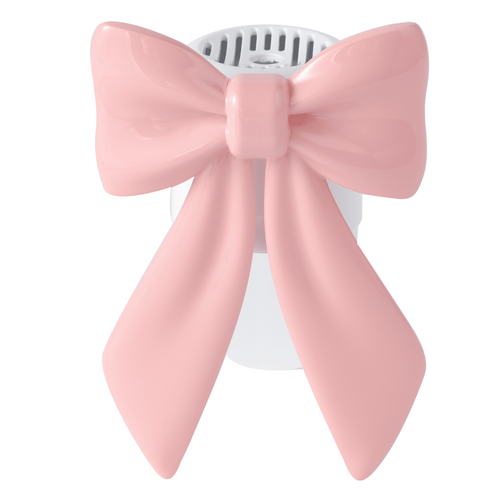 Close-up front view of a white plug-in warmer topped with a glossy pink bow-shaped decorative cover