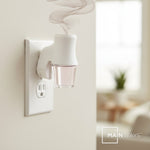 Mainstays plug-in diffuser shown installed in wall outlet with a glass oil refill releasing stylized vapor