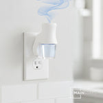 White plug-in diffuser in a wall outlet holding a clear bottle of light blue Mainstays oil with scented vapor
