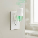 Mainstays plug-in diffuser with green Palm Tree Breeze refill inserted, mounted in a wall outlet