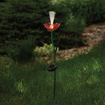 Illuminated red rose garden stake with glowing fiber-optic center set in grassy outdoor landscape at dusk