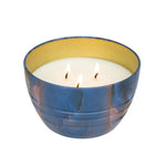 Blue and copper marbled bowl candle with three lit wicks and pale yellow interior, on white background.