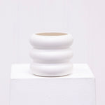 Matte white ceramic bubble planter displayed on a white pedestal against a pale backdrop