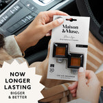 Hands holding Maison & Muse Marilyn car vent clip two-pack packaging inside a vehicle