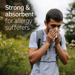 Outdoor lifestyle shot of a man blowing his nose with overlaid text about strong and absorbent tissues for allergies