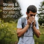 Outdoor image of a man sneezing in a natural setting with overlay text about strength and absorbency for allergy sufferers.