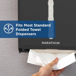 Hand pulling a white folded towel from a black Marathon dispenser with a blue banner stating it fits most standard dispensers