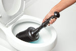 Hand gripping a black accordion-style plunger placed inside a white toilet bowl