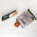 Matter compostable bag partially open with apples spilling out beside the product box on a white surface.