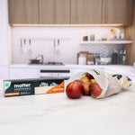 Matter box and a semi-transparent compostable bag filled with apples displayed on a kitchen counter.