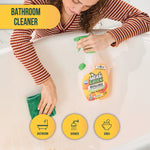 Top-down lifestyle image of a person cleaning a bathtub with a cloth while a Mean Green refillable bottle sits nearby.