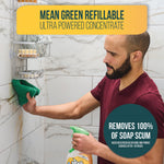 Man cleaning tiled shower with a cloth while holding a Mean Green refillable bathroom cleaner bottle in the foreground.