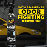 Meguiar’s Air Re-Fresher bottle staged on reflective surface with bold text promoting odor fighting technology.