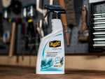 Meguiar's Re-Fresher spray bottle standing on a workbench with tools and pegboard blurred in the background