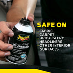 Close-up of hands pressing the nozzle on a Meguiar's Air Re-Fresher can with text listing safe surfaces like fabric and upholstery.