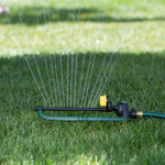 Melnor oscillating sprinkler spraying multiple thin water streams across a lawn with hose attached